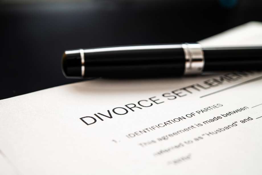 A close-up of a divorce settlement document and a black pen.