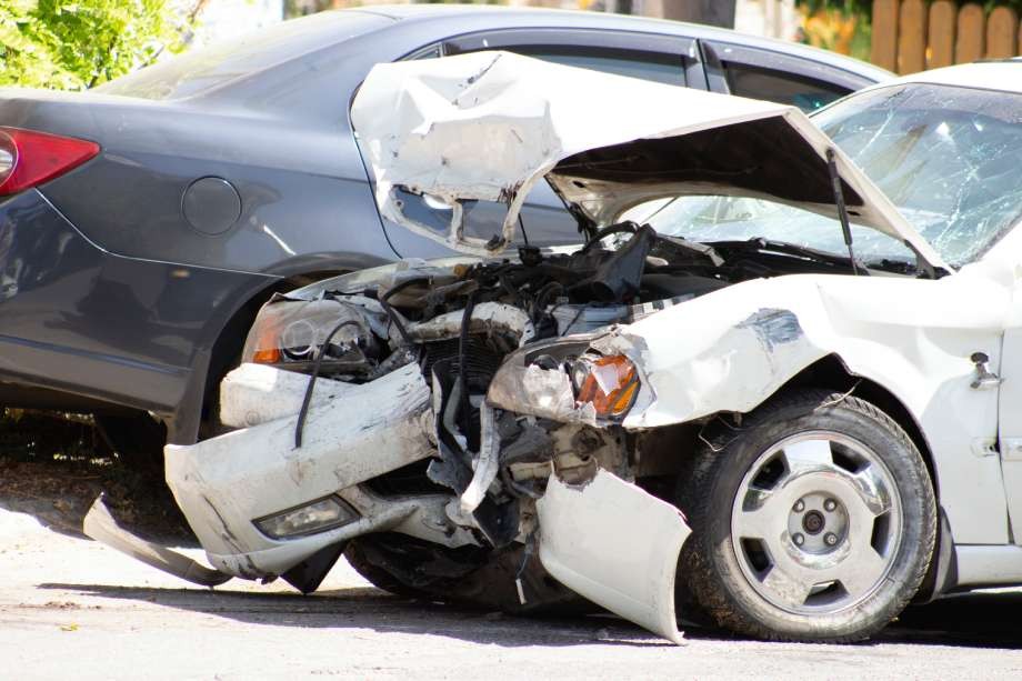 Severe front-end damage to a white car after a rear-end collision.