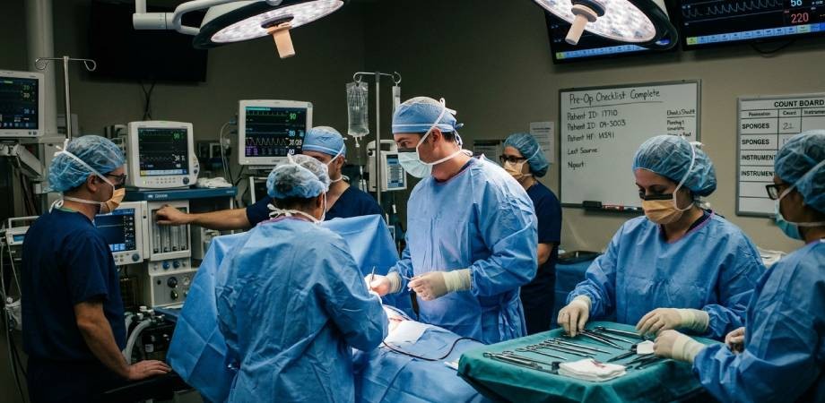 A surgical team in scrubs and masks performs an operation in a well-equipped operating room with medical monitors and instruments, highlighting the importance of awareness about common types of surgical errors NYC hospitals strive to prevent.