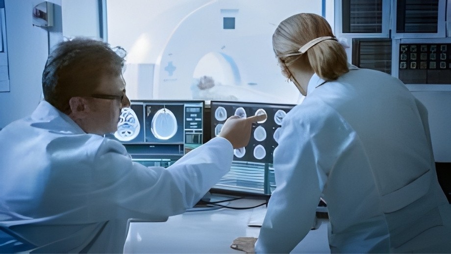 Two medical professionals analyze brain scan results on computer monitors in a diagnostic lab.