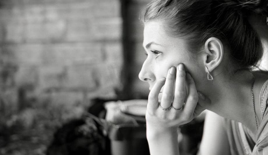 Black and white photo of a woman in profile resting her chin on her hand, looking thoughtfully into the distance, capturing the quiet contemplation seen during emotional distress claims amid COVID-19 in Brooklyn NYC.