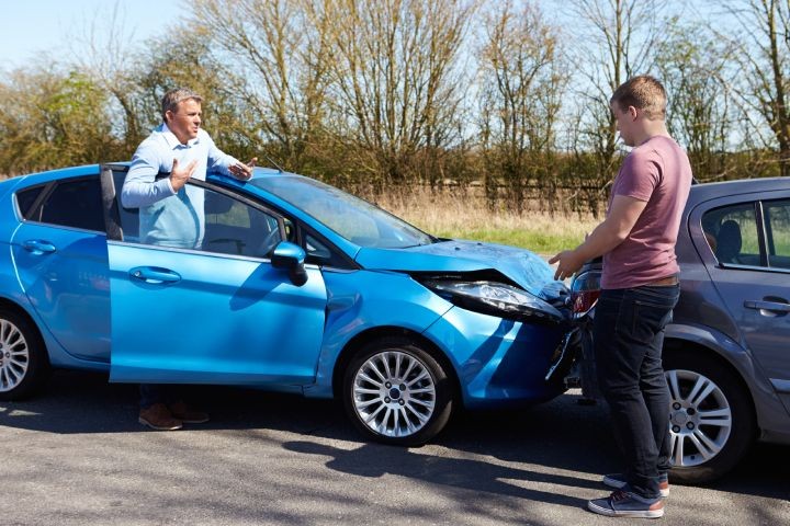 Two drivers exchange information after a blue car is hit.