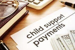 Official document for child support payments on a desk with a calculator and cash.
