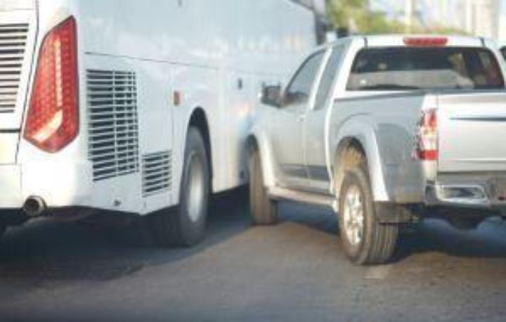 A white bus and a silver pickup truck are involved in a minor collision on a paved road. Learn more about your legal options if you are injured in a New York bus accident.