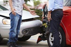 Two people stand near the front of their cars after a collision, with visible bumper damage—highlighting the most common injuries resulting from rear-end collisions.