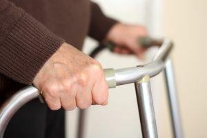 Close-up of a senior man's hands gripping a metal walker.