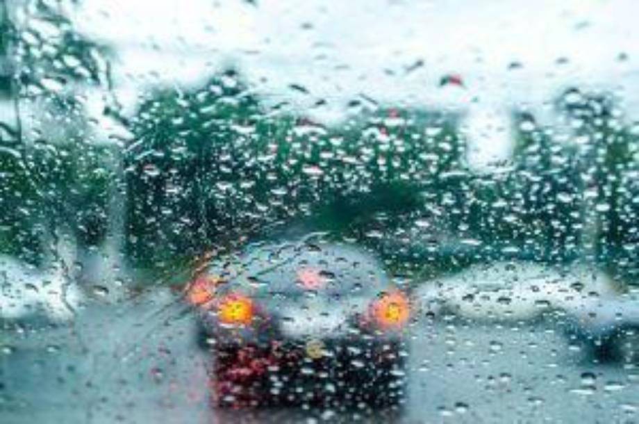Rain-covered car window with blurred vehicles and taillights outside on a wet, overcast day—a reminder of the importance of following Tips to Prevent New York Car Accidents in Bad Weather.