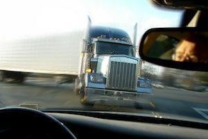 View from inside a car as a large semi truck approaches head-on, creating a sense of imminent collision—raising questions about determining fault in a truck accident NYC.
