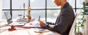 female attorney reviewing legal documents at desk with gavel and scales of justice