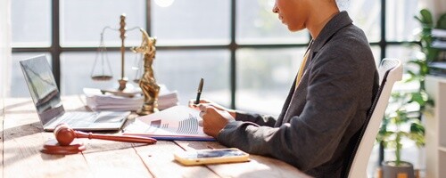 female attorney reviewing legal documents at desk with gavel and scales of justice