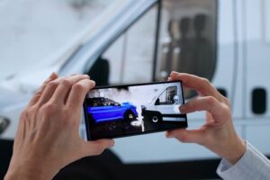 adjuster photographing vehicle collision damage with smartphone at accident scene