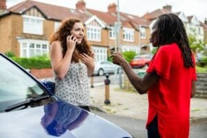 two people exchanging information beside vehicle following street collision