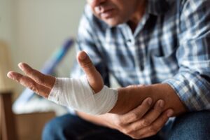 person in plaid shirt displaying bandaged hand and wrist injury