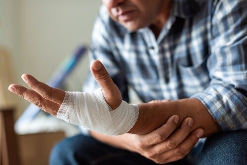 person in plaid shirt displaying bandaged hand and wrist injury