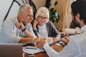 older couple reviewing documents with professional advisor at office desk